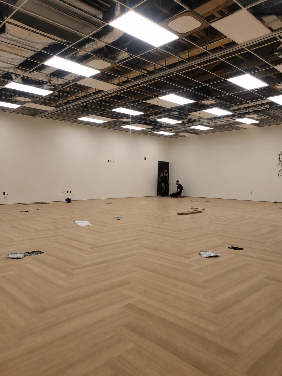 Geometrix Flooring & Design installation crew laying a herringbone wood-look LVT floor on a commercial fit-out