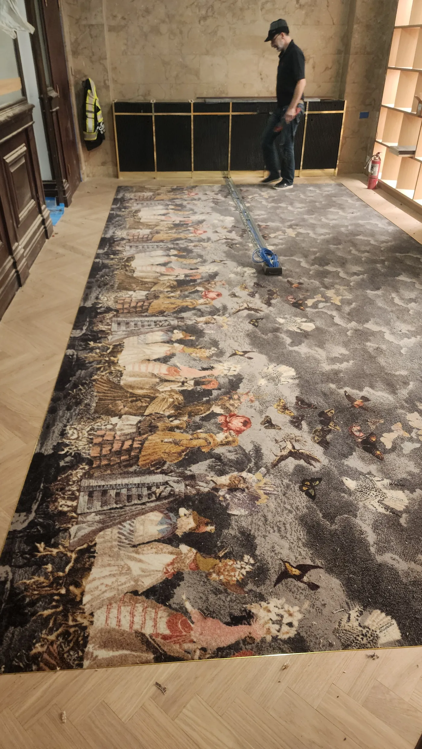 Hand-illustrated bespoke art carpet installed flush against herringbone hardwood — luxury custom flooring installation by Geometrix Flooring & Design