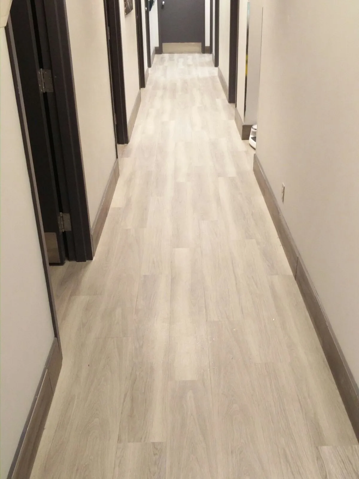 Medical office corridor with light wood-look luxury vinyl tile installed by Geometrix Flooring & Design