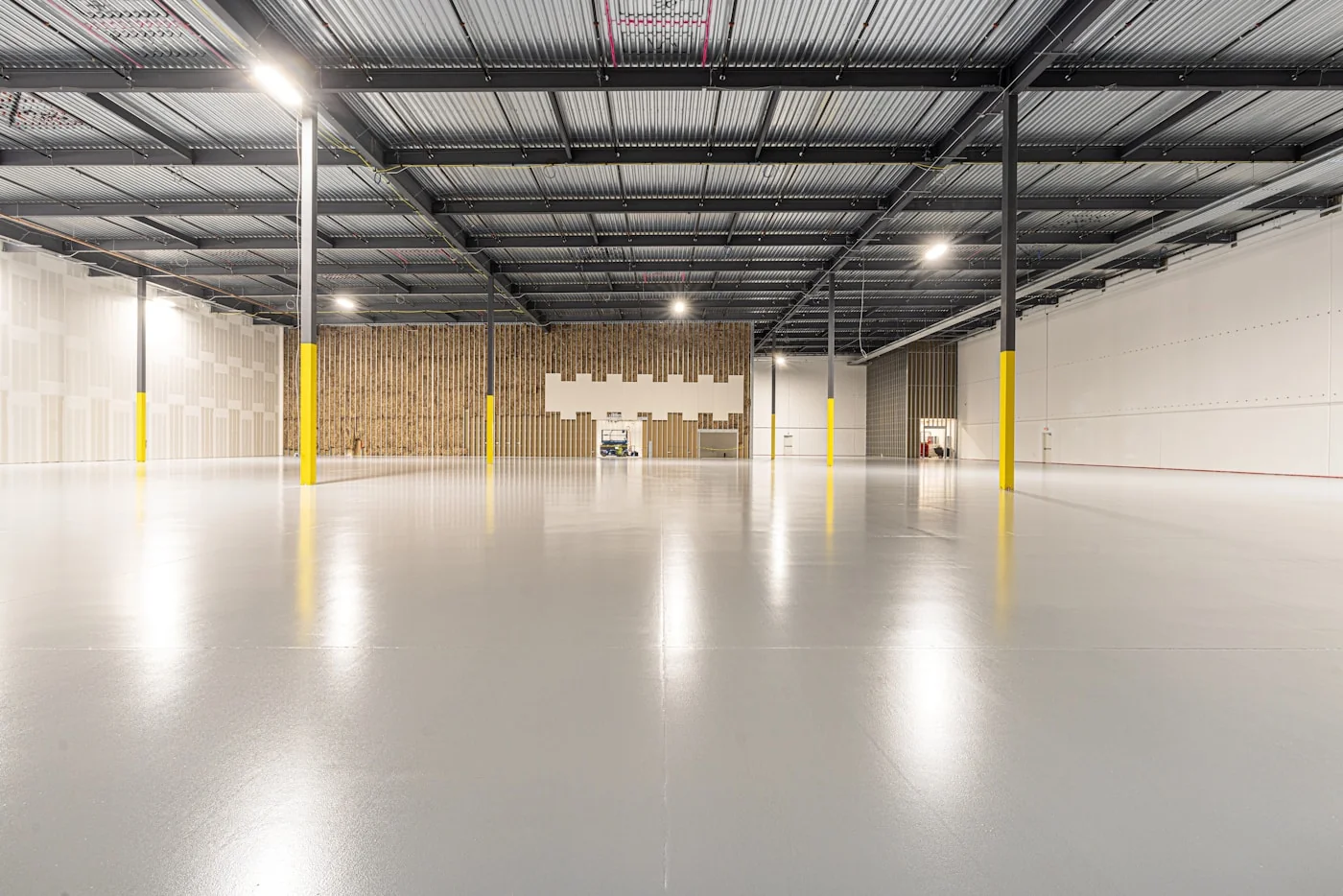 Empty industrial warehouse with a polished-concrete / epoxy floor system delivering a slip-rated, hard-wearing finish